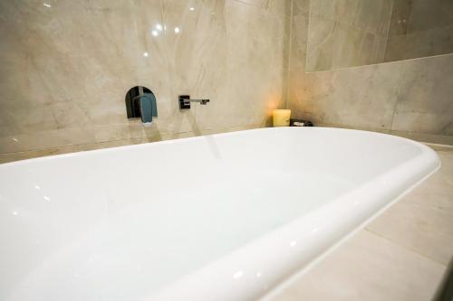 a white bath tub in a bathroom with a soap dispenser at Adelaide Style Accommodation-Getaway in North Adelaide- close to city in Adelaide