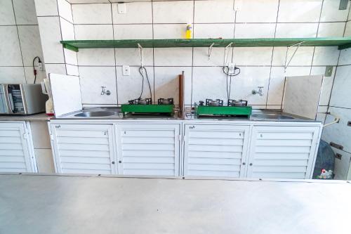 a kitchen with white cabinets and green sinks at Parada da Cal Beach Torres in Torres