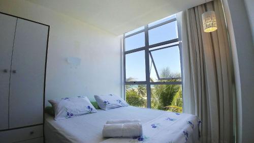 een slaapkamer met een bed en een groot raam bij Areias do Mar ! Charmoso e com Ar na Sala A318 in Barra de São Miguel
