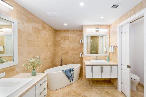 a bathroom with a tub and two sinks and a toilet at Club Se7en at Beachcomber in Upper Land