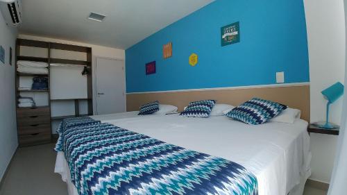 um quarto com uma grande cama branca com paredes azuis em Areias do Mar ! Confortável e com Ar na Sala A315 em Barra de São Miguel