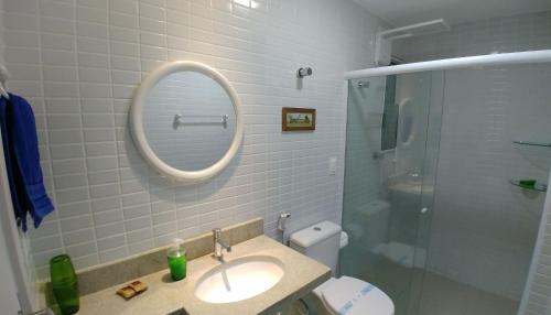uma casa de banho com um lavatório, um espelho e um chuveiro em Areias do Mar ! Confortável e com Ar na Sala A315 em Barra de São Miguel
