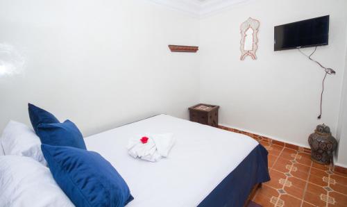 a bedroom with a white bed with blue pillows at Hotel Al kassaba in Chefchaouene