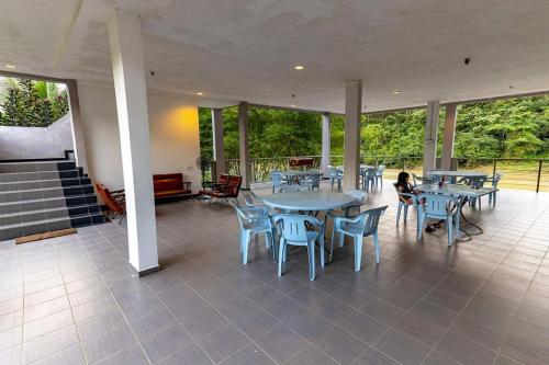 un gran patio con mesas, sillas y ventanas en RIVERSIDE PALM INN SG LEMBING, en Sungai Lembing