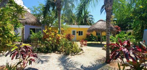 a yellow and white house with palm trees and plants at Aldea Bek in Puerto Morelos