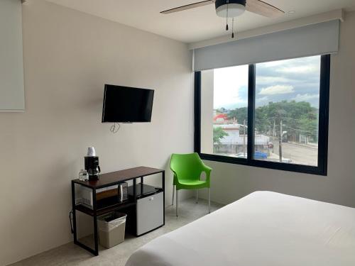 een slaapkamer met een bed, een groene stoel en een raam bij Las Palmas Studios in Cancun