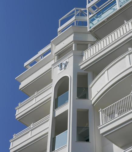 a white building with balconies and a blue sky at Hotel Tiffany's in Riccione