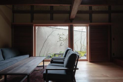 a living room with a table and chairs and a window at 滔々 阿知の庄 蔵の宿 toutou Achinosho Kura no Yado in Kurashiki