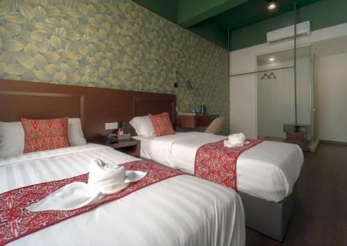 a hotel room with two beds and a painting on the wall at East Riverine Boutique Hotel in Kuala Lumpur