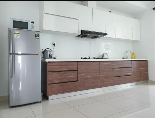 Una cocina con refrigerador de acero inoxidable y gabinetes de madera. en Mansion One 3 Bedroom SEAVIEW Gurney Georgetown 1-13Pax, en George Town