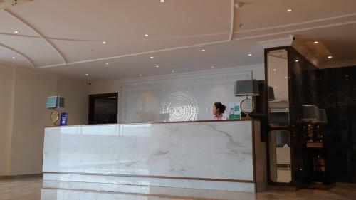 a woman standing behind a marble counter in a lobby at OAKTREE HOTEL in Morbi