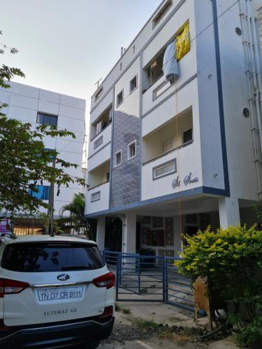 a white car parked in front of a building at S4 Sruthi Service Apartments in Chennai