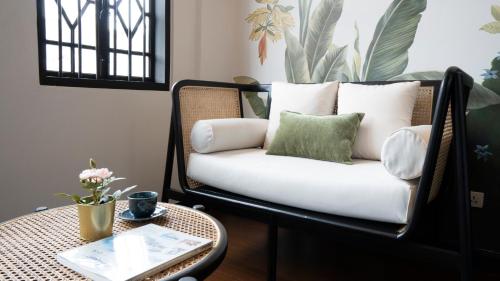 a chair with pillows on it next to a table at BAAN 125 STAY Phuket in Phuket Town