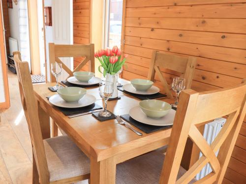 a wooden table with plates and bowls and flowers on it at Ramblers' Rest Lodge in Windermere