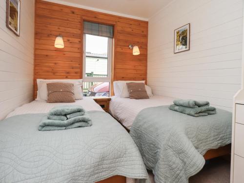 two beds in a room with wooden walls at Ramblers' Rest Lodge in Windermere