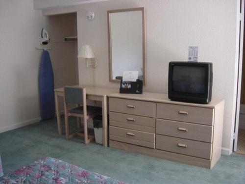 a room with a desk with a television and a mirror at Prestige Inn in Lafayette