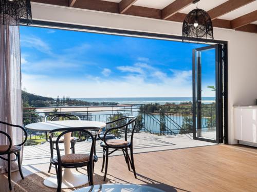 a balcony with a table and chairs and a view of the ocean at The Beach Rooms in Nambucca Heads