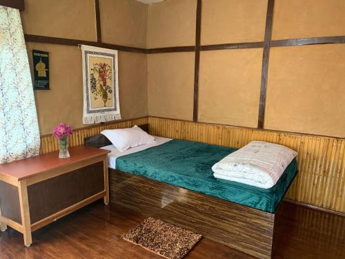 a small bedroom with a bed and a table at Kazi Retreat in Pakyong