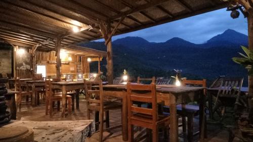 a dining room with tables and chairs with mountains in the background at Made Oka Homestay and Warung in Munduk