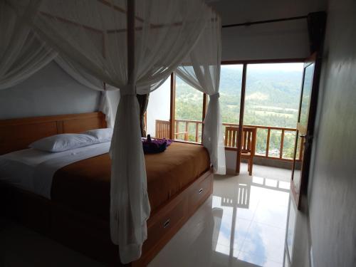 a bedroom with a bed with a view of a balcony at Made Oka Homestay and Warung in Munduk