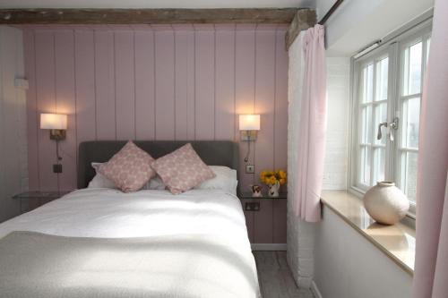 a bedroom with a bed with pink walls and a window at The Hayloft - Cheshire in Crewe