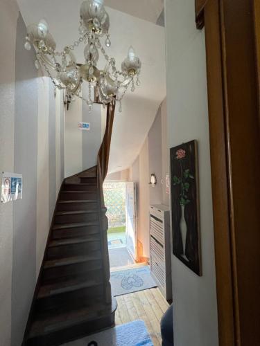 a hallway with a staircase with a chandelier at Chambre D'hôte Villa Maurice in Étretat