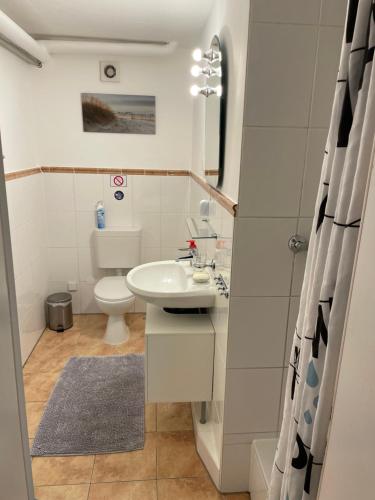 a white bathroom with a sink and a toilet at Messe Apartment Berlin in Berlin