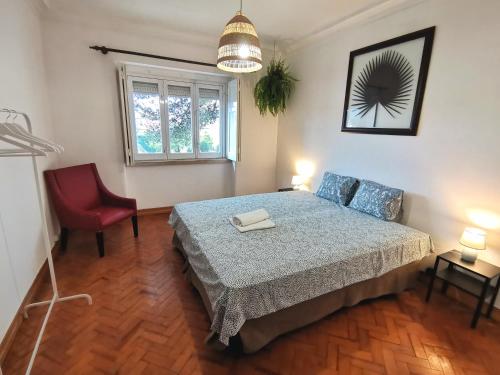 a bedroom with a bed and a red chair at Botanique Guesthouse in Cascais