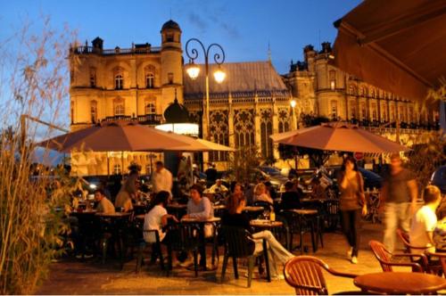 um grupo de pessoas sentadas em mesas em frente a um edifício em Saint-Germain-en-Laye: Grand studio en Centre Ville à 2 minutes du RER em Saint-Germain-en-Laye