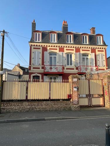 une grande maison en briques rouges avec une clôture en bois dans l'établissement Chambre D'hôte Villa Maurice, à Étretat