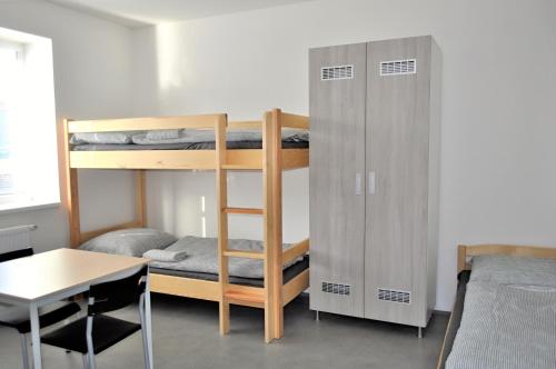 a dorm room with bunk beds and a desk and a table at Ubytovna a Cykloubytovna Koupaliště Kadaň in Kadaň