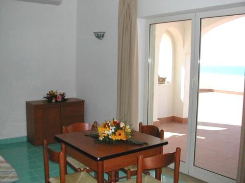 a dining room table with chairs and a table with flowers on it at Casa Vacanze Elianto in Anzio