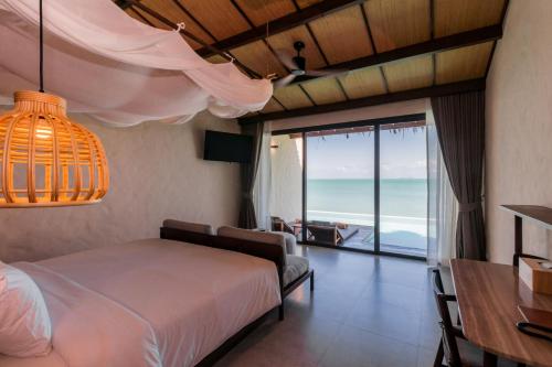 a bedroom with a bed and a view of the ocean at The Flow Samui Beach Resort in Mae Nam