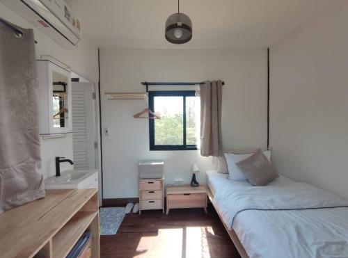 a bedroom with a bed and a sink and a window at Morinaka Craftfe & Poshtel in Ban Na Muang