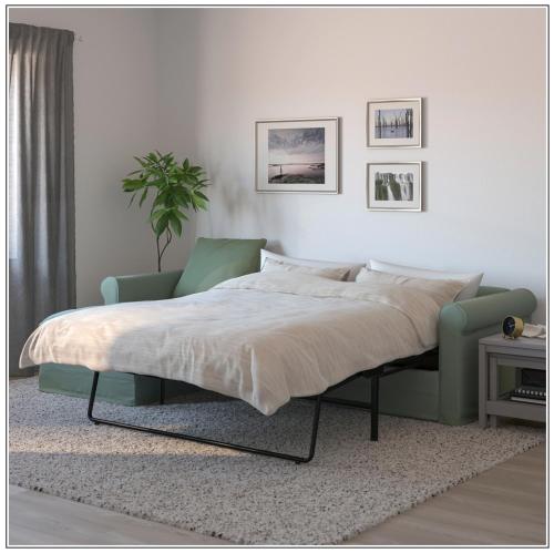 a bedroom with a bed and a green chair at Perfect get away - Cosy Cabin in the Woods in Diessen