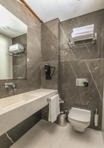 a bathroom with a sink and a toilet and a mirror at Henna Hotel Istanbul in Istanbul