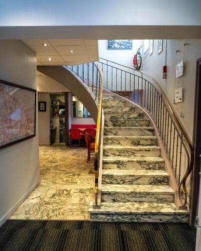 a spiral staircase in a building with a stair case at Au Primerose Hôtel in Argelès-Gazost