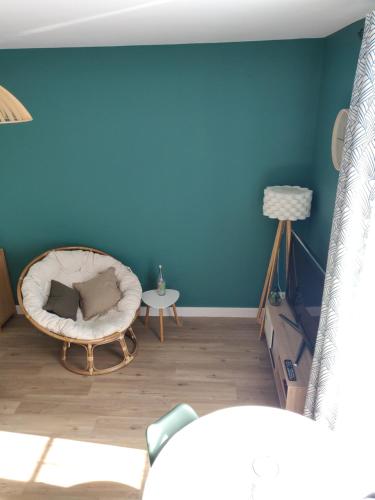 ein Wohnzimmer mit einer blauen Wand und einem Stuhl in der Unterkunft Scandinave - proche gare & centre-ville - stationnement - cour intérieure table & chaises in Saint-Brieuc