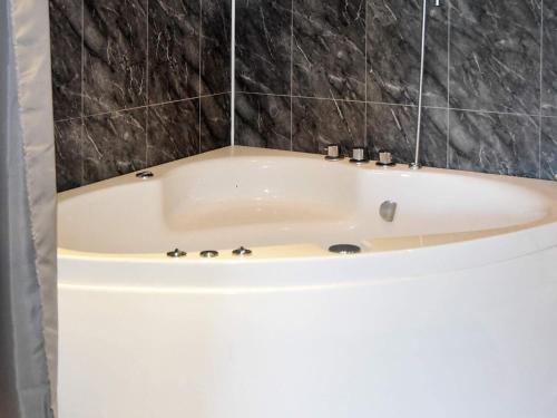 a white bath tub in a bathroom with black tiles at Holiday home SANDANE II in Sandane