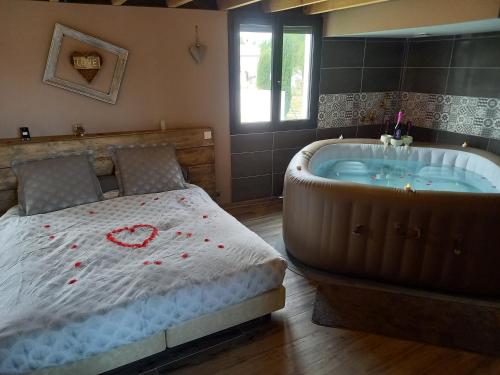 a bedroom with a bed and a tub with a heart on it at COSY-LOFT Industriel , jacuzzi , WIFI , 6 personnes max in Aigues-Vives