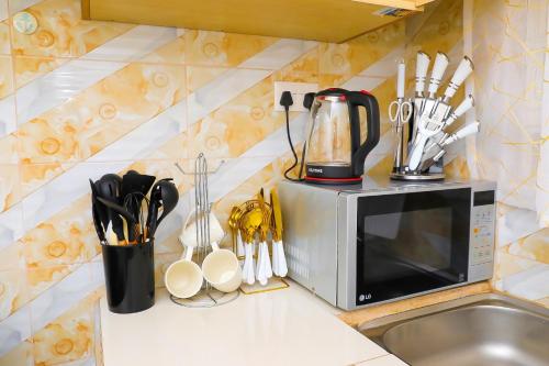 eine Küchentheke mit einer Mikrowelle und Küchenutensilien in der Unterkunft The Ivy Suite- one bedroom 3 mins away from Ruiru Rainbow Resort in Ruiru