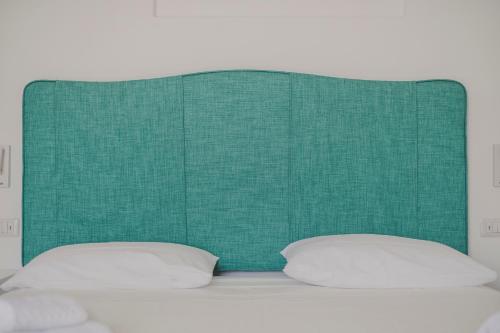 a green headboard with two pillows on a bed at Villa Nettuno in Positano
