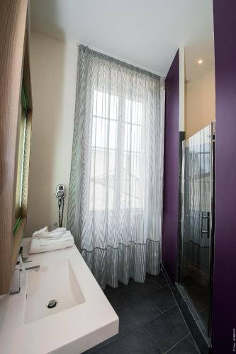 une salle de bain avec un lavabo blanc et une fenêtre dans l'établissement Hôtel François Premier Cognac Centre, à Cognac