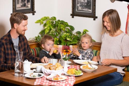 une famille assise à une table et mangeant de la nourriture dans l'établissement Hotel garni Weberhäusl, à Strobl