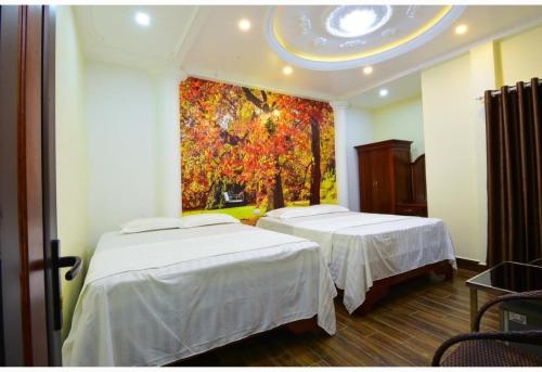 two beds in a room with a painting on the wall at HAPPY GUEST HOUSE in Hai Phong
