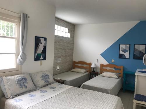 1 dormitorio con 2 camas y ventana en Casa praia Armação Matadeiro Floripa, en Florianópolis