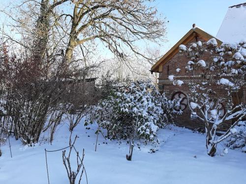 a house covered in snow in a yard at Ferienhaus Rosengarten in Loxstedt
