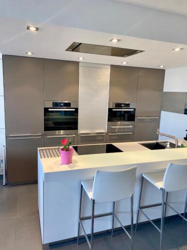 une cuisine avec des appareils en acier inoxydable et un comptoir avec des chaises dans l'établissement Appartement de prestige vue mer place de parking, à Le Touquet-Paris-Plage