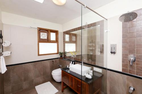 a bathroom with a toilet and a glass shower at Destiny - The Farm Resort in Ooty