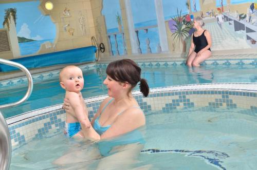 a woman holding a baby in a swimming pool at Newby Bridge Hotel in Newby Bridge